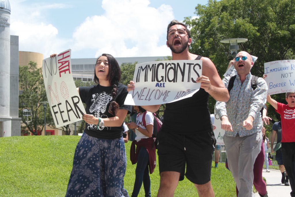 Ryan Almodovar, a senior majoring in biology, holds a sign that reads "Immigrants are welcome here," as he protests on the GC lawns.