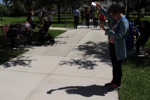 Karla Buergo:Phychology senior uses a pinhole camera with a notecard to view the eclipse