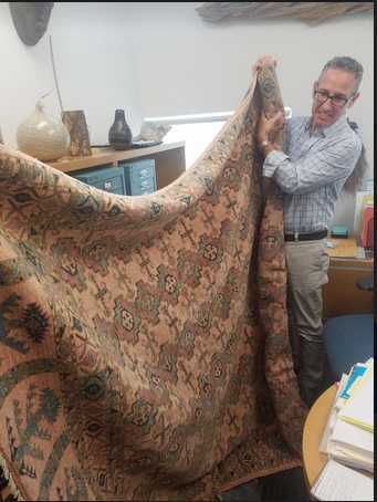 Senior Director of Strategic Initiatives Pedro Botta displaying the hand-woven rug that will be on display in the exhibit.